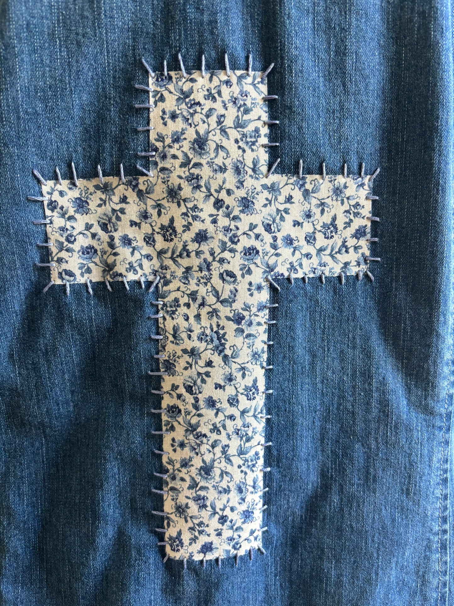 Floral-patterned cross patch on blue denim fabric