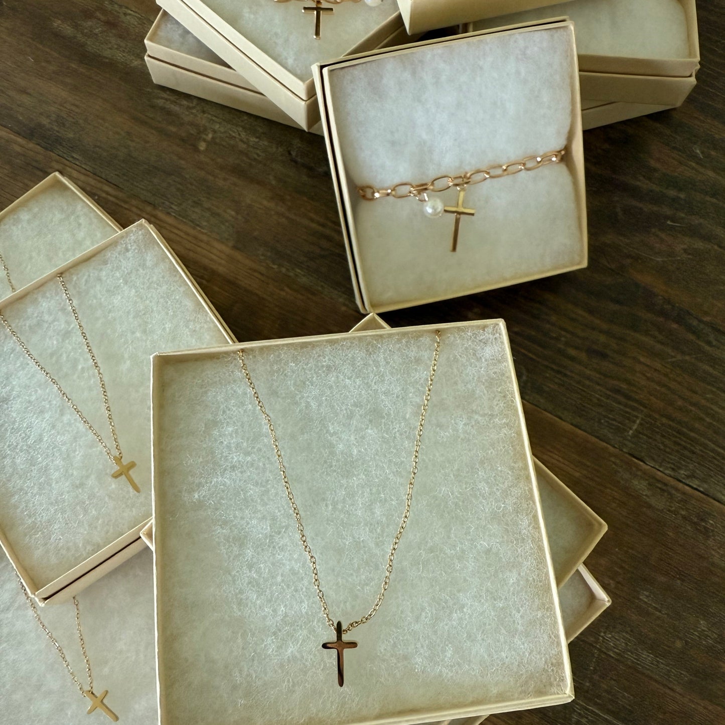 Jewelry boxes with gold cross necklaces and gold cross bracelets on a wooden surface
