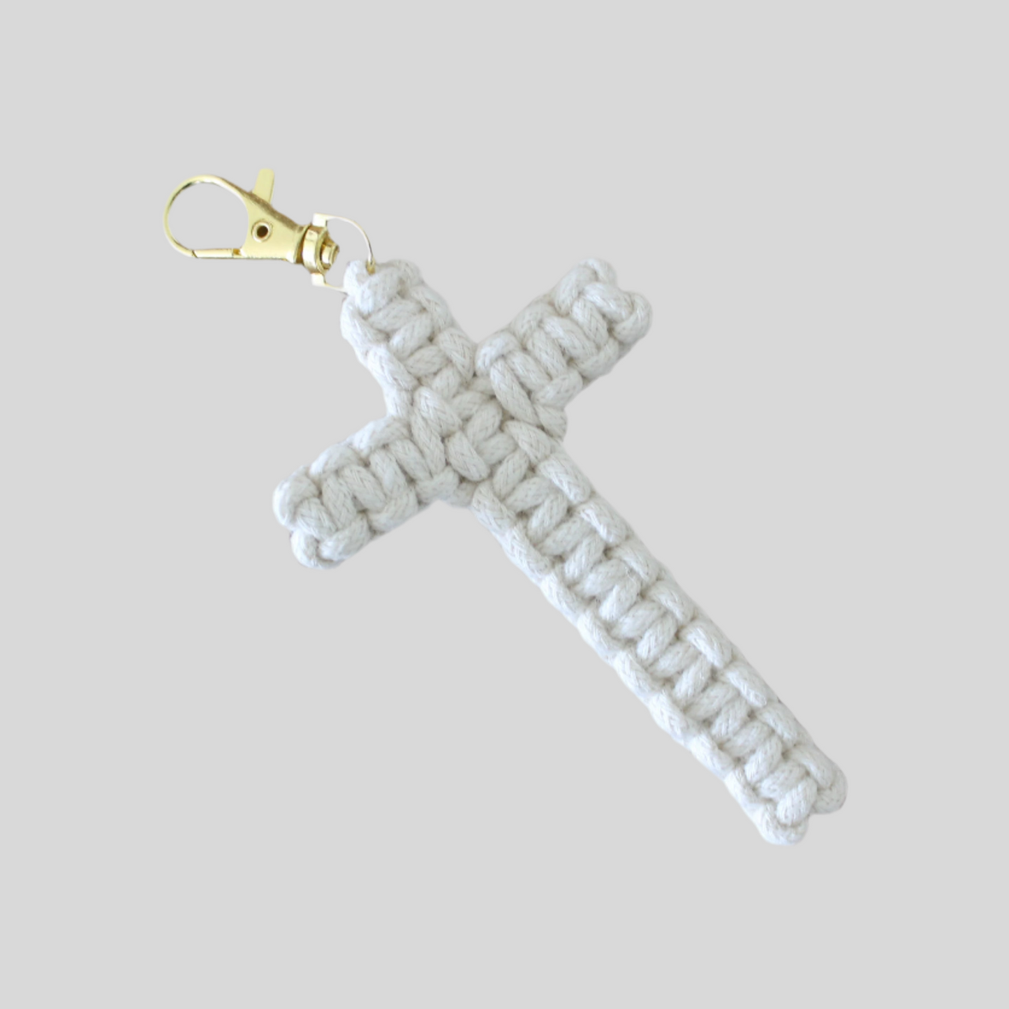 A white Macrame' cross keychain with a gold-colored clip, isolated on a white background.