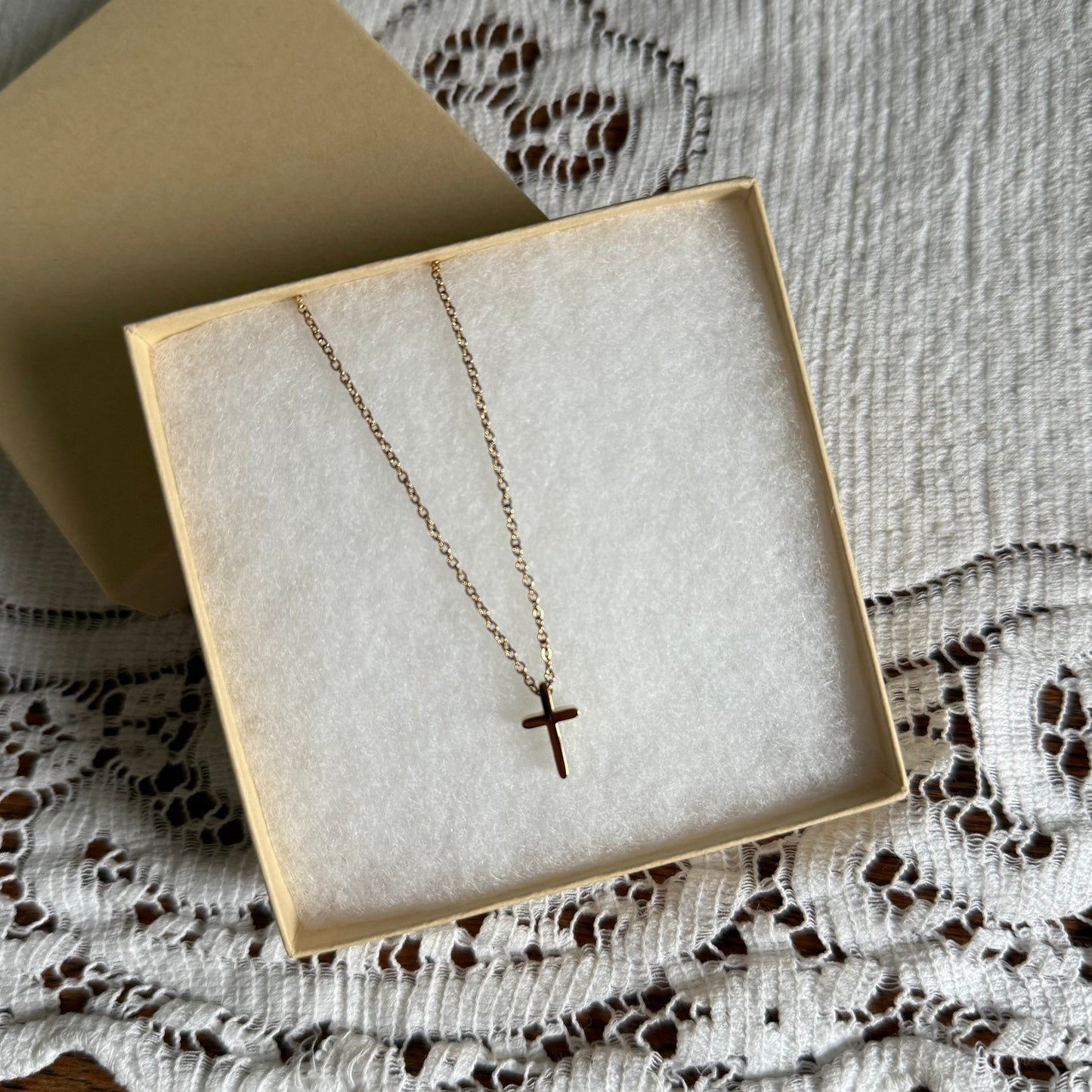Necklace with a cross pendant in a box on a textured surface