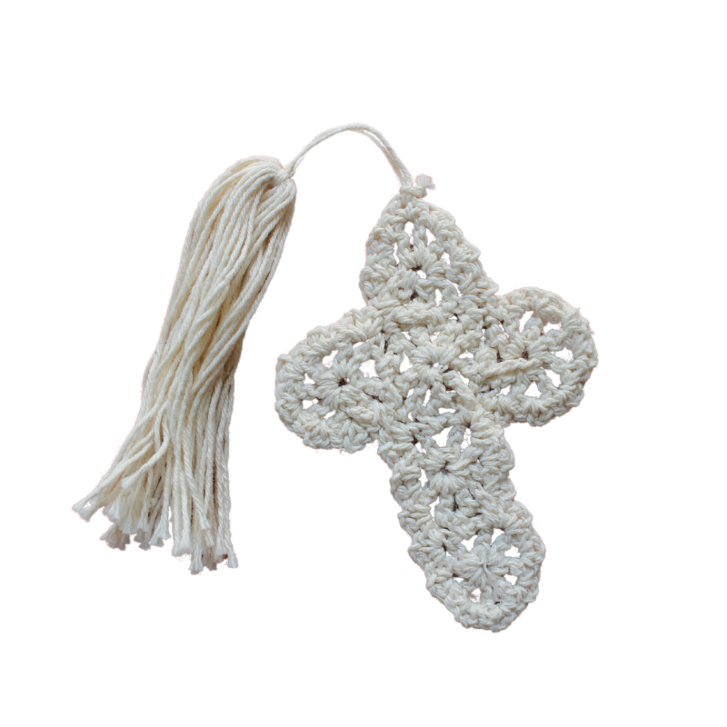 A beige crochet bookmark in the shape of a cross with a tassel.